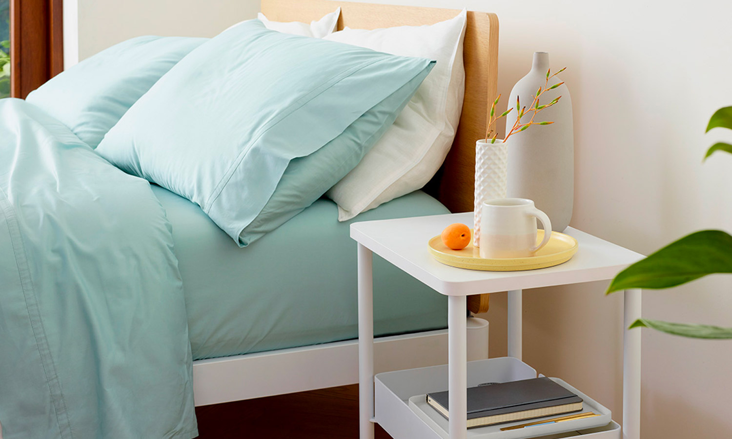 white nightstand with a coffee cup and books on it 