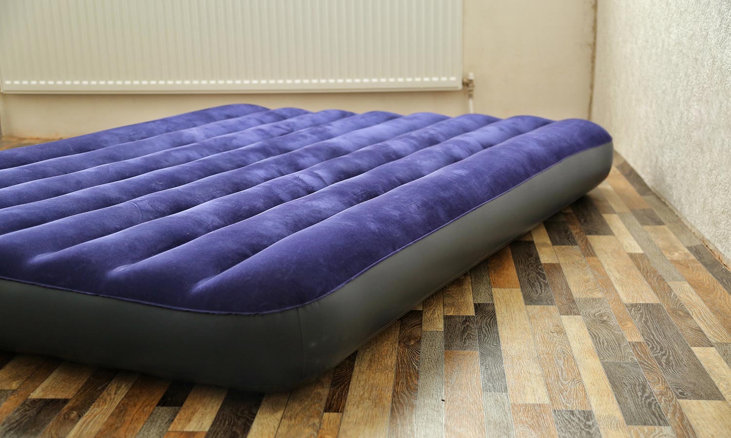 An inflatable air mattress sits on a hardwood floor