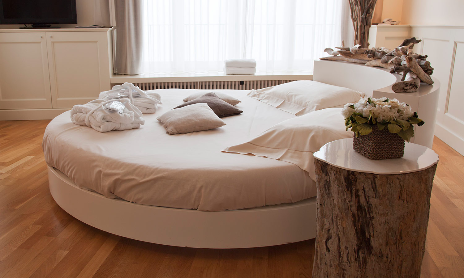 A round bed with pillows on top in a bright and sunny room.