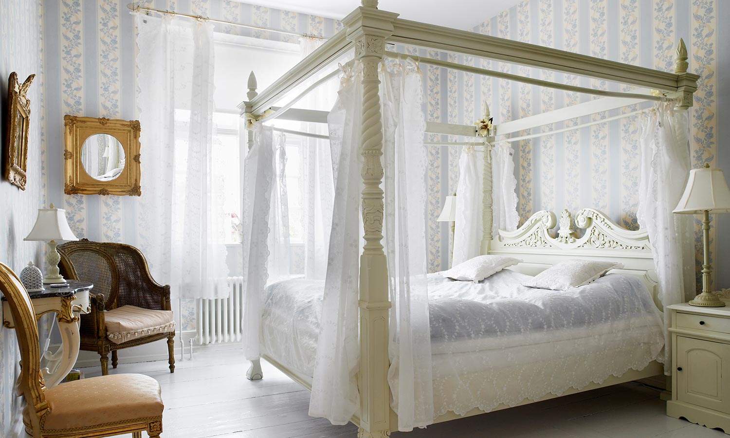 A canopy bed with thin and light fabric hanging from the top corners.