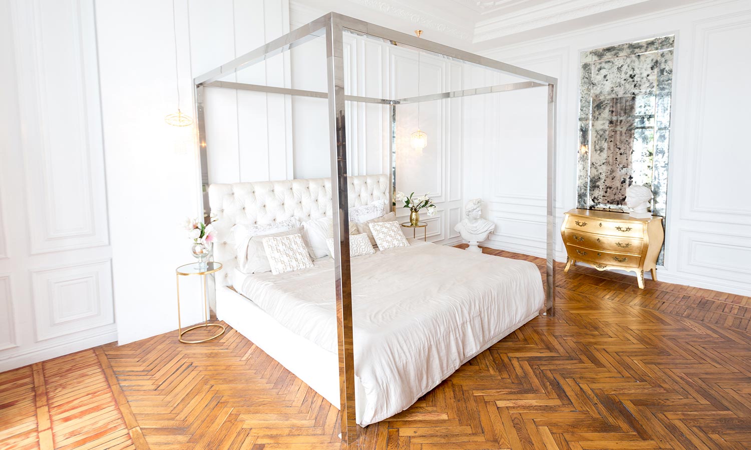 A canopy bed with a shiny metallic frame and no fabric hanging from it.