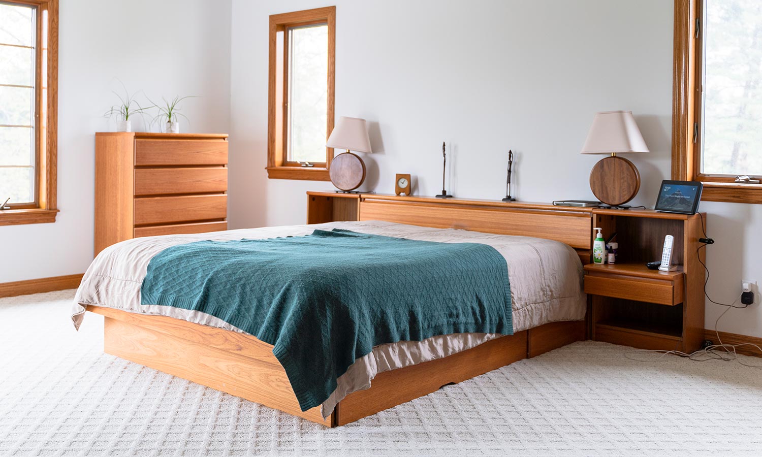 A bed on a sleek low platform with shelves and drawers built into the headboard