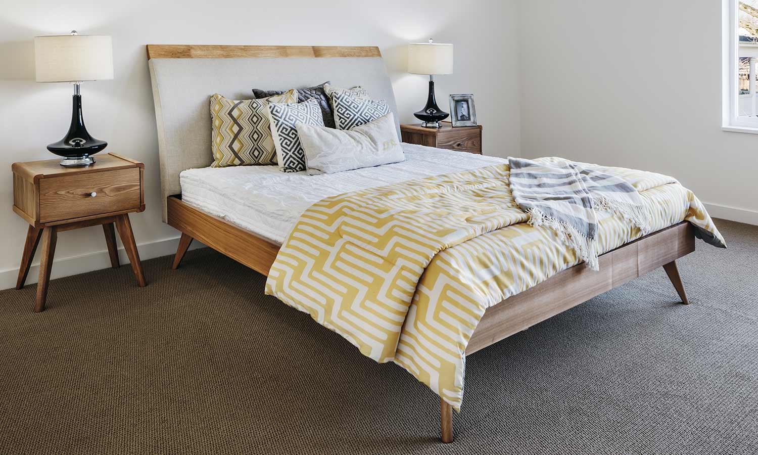 A bed with the legs sitting at an angle with multi-patterned pillows and blankets on top.