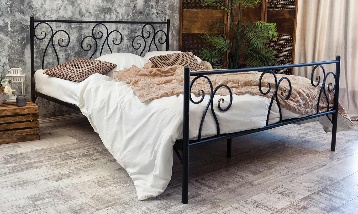 A simplistic iron bedframe with delicate swirls of metal wover int he headboard and footer.