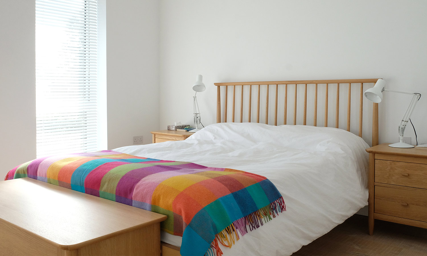 A wooden bedframe where tall cylindrical spindles make up the headboard.