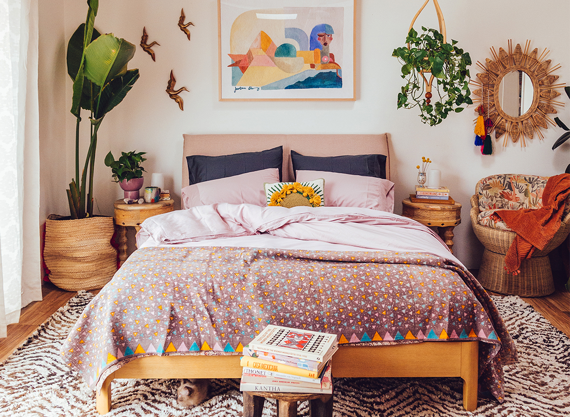 bedroom with pink sheets, plants, and wall decor