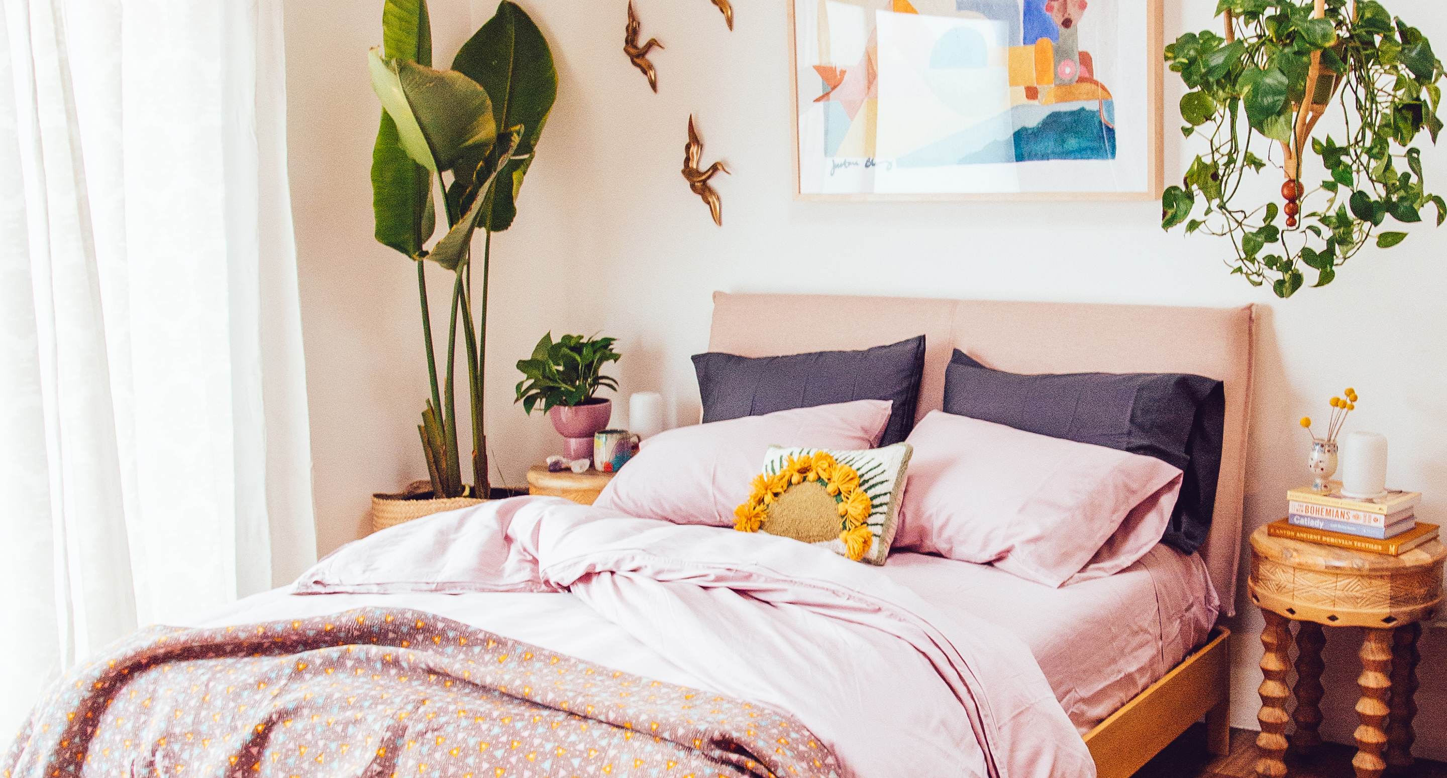 bedroom with pink sheets, plants, and wall decor